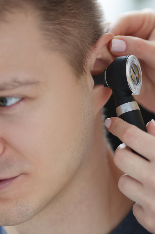 a man has his ear examined with an otoscope